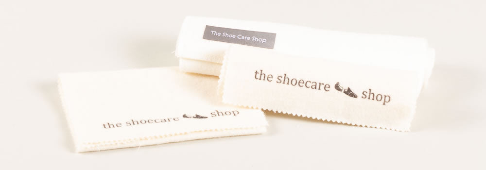 Close-up of soft shoe shine cloths with "the shoecare shop" logo, conveying a clean, professional, and accessible feel.