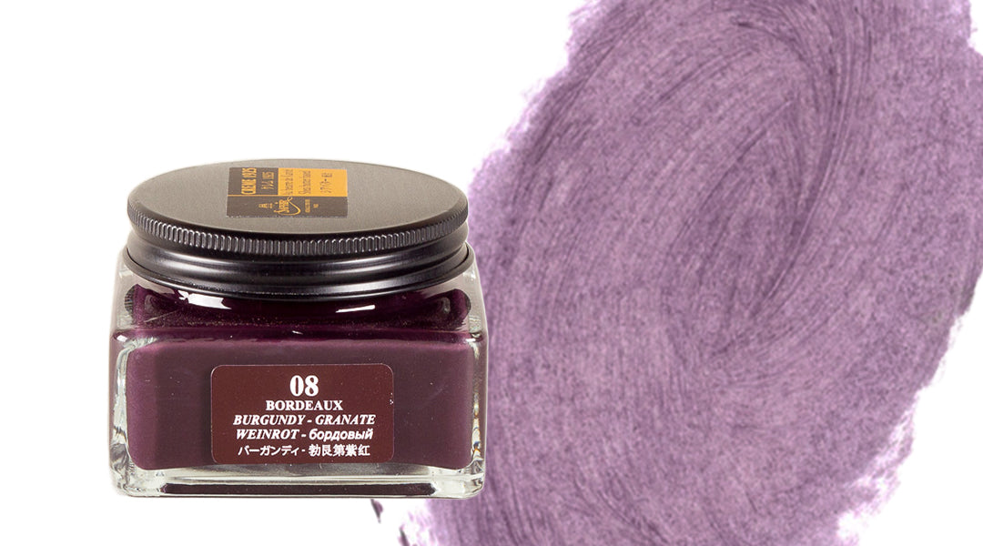 A square glass jar of Bordeaux Burgundy-Granate ink with a black lid is shown next to a rich, textured purple ink swatch on a white background.