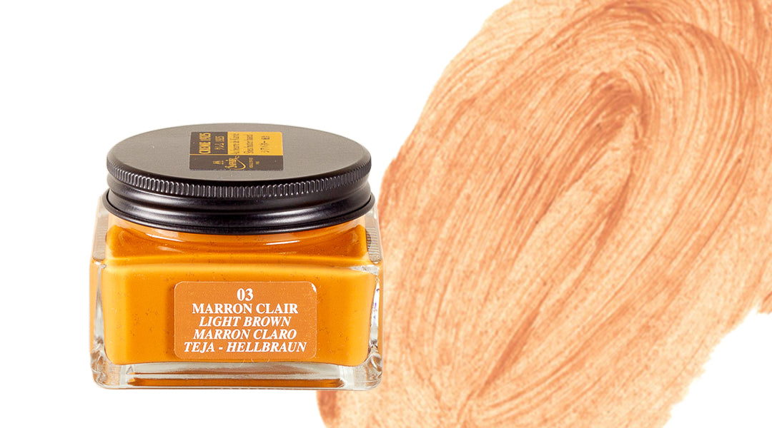 A small glass jar of light brown paint labeled 03 Light Brown sits next to a large brushstroke of the same warm, golden-brown color on a white background.