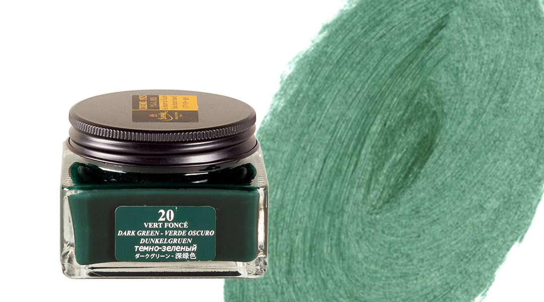 A square glass ink bottle labeled 20 VERT FONCÉ with dark green ink inside sits next to a large swatch of dark green ink brushed on a white background.
